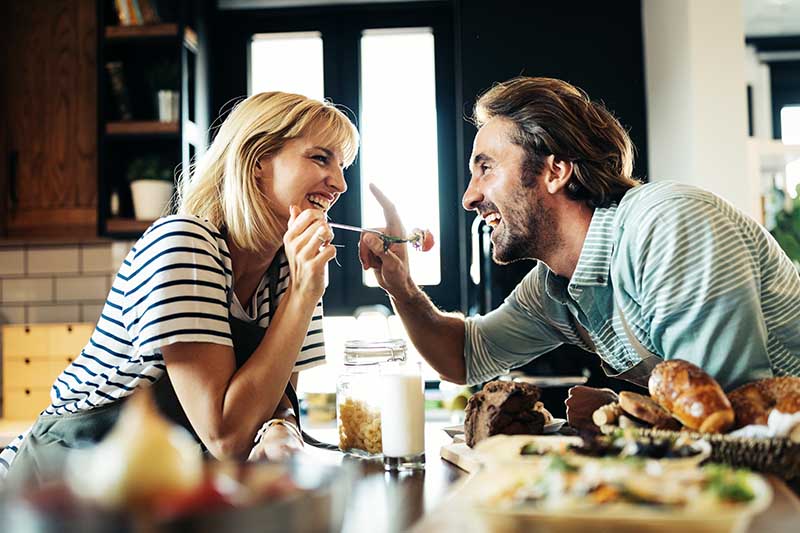 Beautiful young lovely couple is smiling while cooking together in kitchen at home