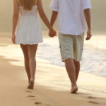 Couple taking a walk holding hands on the beach