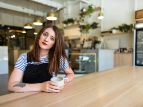 Woman in black and white shirt under underalls with coffee